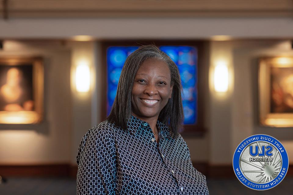 Christa Jackson, Ph.D., with a coin that says 博彩网址大全 Research Institute Fellow