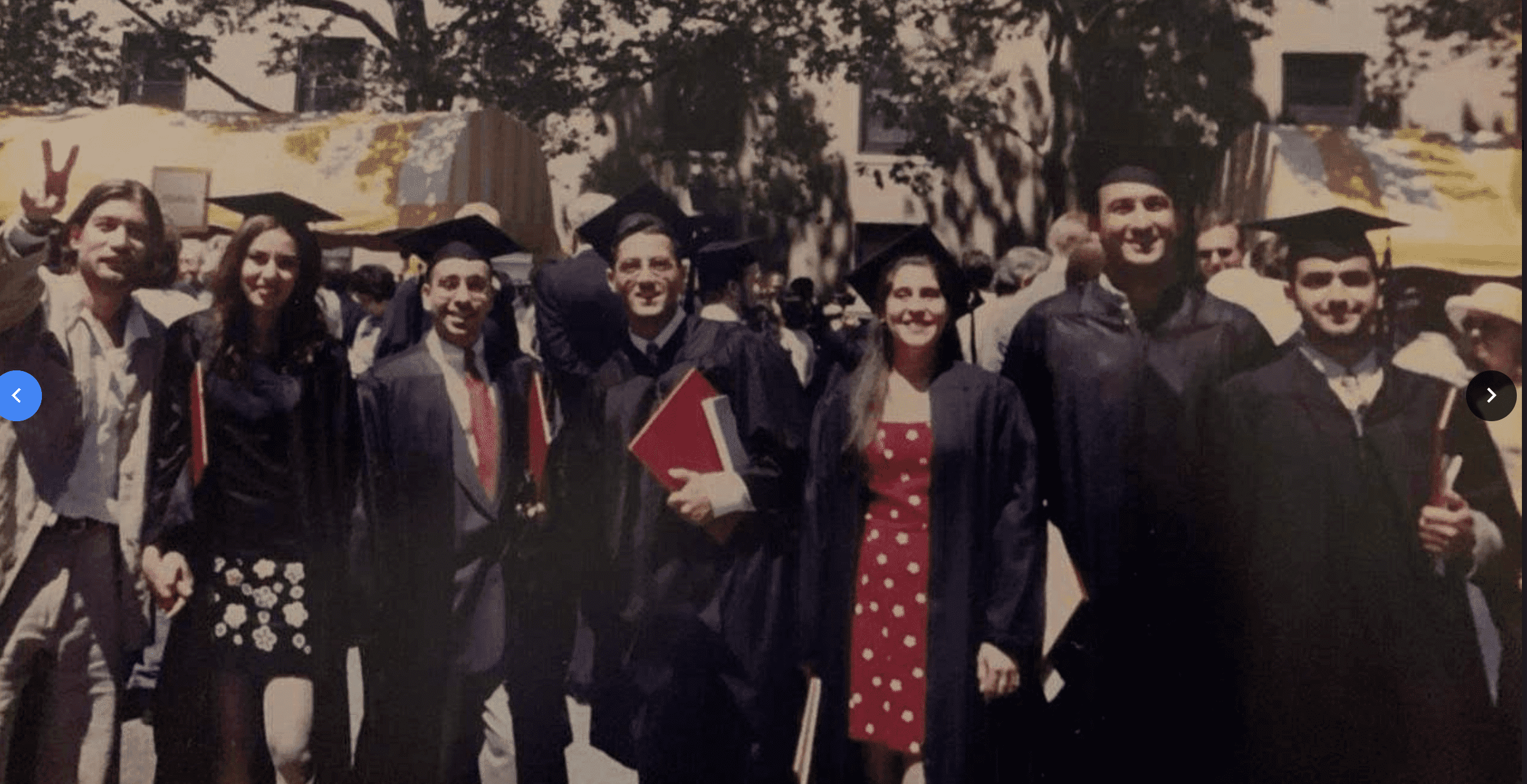 A group of graduates in caps and gowns smile at the camera.