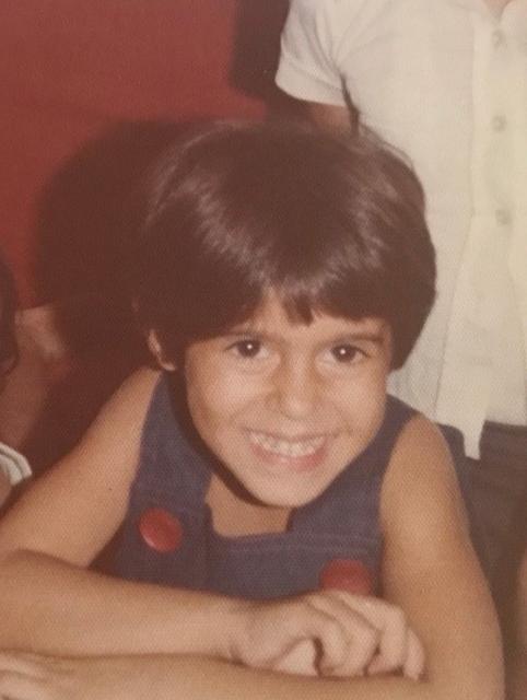 Alameh as a child, posing with a smile.